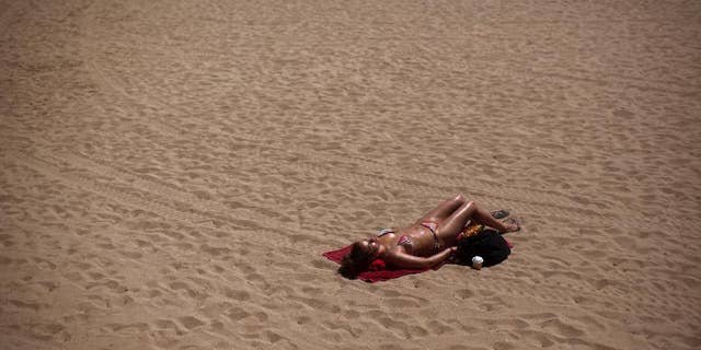 A woman sunbathes in a beach in Barcelona, Spain, Friday, May 15, 2015. The Iberian Peninsula has experienced record high temperatures for May as thermometers shot up to levels normally only seen in midsummer. (AP Photo/Emilio Morenatti)