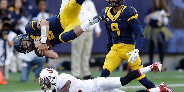 Stanford's Ronnie Harris (21) upends California quarterback Luke Rubenzer (8) during the second half of an NCAA college football game Saturday, Nov. 22, 2014, in Berkeley, Calif. At right is California's Trevor Davis (9). (AP Photo/Ben Margot)