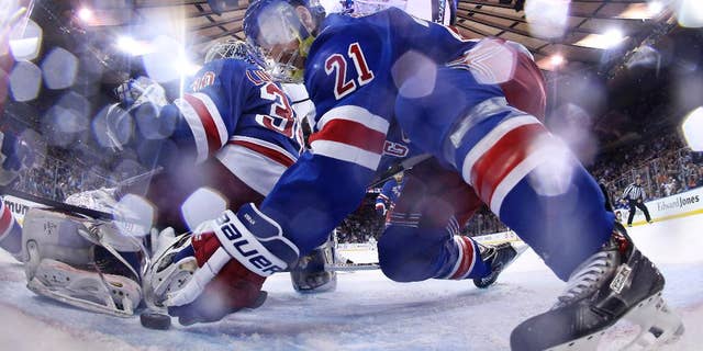 New York Rangers center Derek Stepan (21) reaches to move the puck away from the goal behind goalie Henrik Lundqvist (30) in the third period during Game 4 of the NHL hockey Stanley Cup Final, Wednesday, June 11, 2014, in New York. The Rangers won the game 2-1. (AP Photo/Bruce Bennett, Pool)
