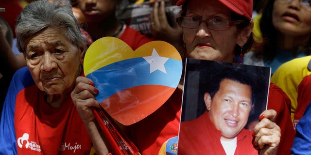 A woman holds a picture of Venezuela's President Hugo Chavez as supporters gather at Simon Bolivar square in Caracas,Venezuela, Sunday Dec. 9, 2012. Chavez is to return to Cuba Sunday for another surgery in his battle against cancer, which has led him to speak publicly of a successor for the first time. Chavez said Saturday that if there are "circumstances that prevent me from exercising the presidency further" Vice-President Nicolas Maduro should replace him for the remainder of his term.(AP Photo/Fernando Llano)