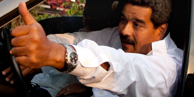 April 12, 2013: Venezuela's interim President Nicolas Maduro gives a thumbs up as Argentina's soccer legend Diego Armando Maradona sits behind him as they leave after paying their respects at the tomb of late President Hugo Chavez in Caracas, Venezuela.