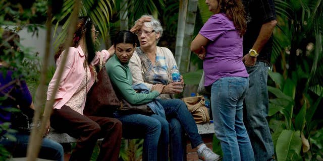 Josefa Alvarez de Gonzalez, center, is comforted by relatives of her husband, Rodolfo Gonzalez, outside the morgue office in Caracas, Venezuela, Friday, March 13, 2015. Rodolfo Gonzalez who was arrested last year during demonstrations against the Venezuela's President Nicolas Maduro government has died in state custody. The family of Gonzalez said that he died while being held at the headquarters of Venezuela's intelligence police. The 64-year-old pilot had been jailed since April 2014 and was awaiting trial on charges related to promoting violence during the protests. (AP Photo/Fernando Llano)