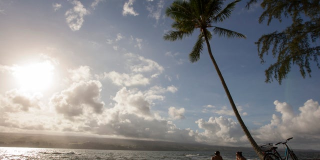 Keenin Ide, left, of Hilo, Hawaii, and Medea Yankova, of Sofia, Bulgaria, sit near Hilo Bay in Hilo Hawaii, Sunday Aug. 30, 2015. Hurricane Ignacio is forecast to weaken and move north of the Hawaiian Islands on Monday and Tuesday. (AP Photo/Caleb Jones)