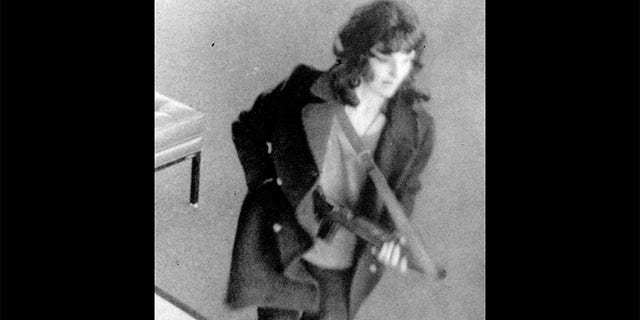 Patty Hearst as "Tania" holds machine gun during the bank robbery in San Francisco.