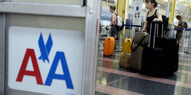 A woman waits in line with luggage to check in for an American Airlines flight at Reagan National Airport in Arlington, Va.