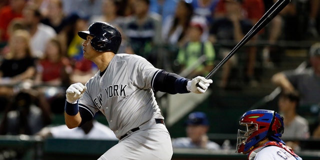 New York Yankees' Alex Rodriguez follows through on a solo home run swing off a pitch from Texas Rangers' Matt Harrison as Rangers catcher Robinson Chirinos watches in the sixth inning of a baseball game Monday,July 27, 2015, in Arlington, Texas. (AP Photo/Tony Gutierrez)