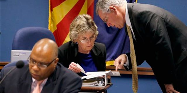 Maricopa County Attorney Bill Montgomery, right, talks with Arizona Legislature child protective services oversight committee co-chair Rep. Kate Brophy McGee, R-Phoenix, as Department of Economic Security Director Clarence Carter, left, refers to notes prior to a committee hearing at the Arizona Capitol Monday, Dec. 16, 2013, in Phoenix. The committee finds out an update on efforts to investigate more than 6,500 abuse and neglect reports that were not investigated by the Child Protective Services state agency in recent years. (AP Photo/Ross D. Franklin)