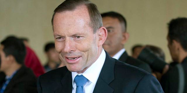 October 20, 2014: Australian Prime Minister Tony Abbott waves as he arrives for the inauguration of Indonesian President Joko Widodo at Parliament in Jakarta. (AP Photo/Mark Baker)