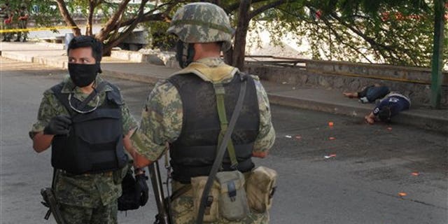 Jan. 8, 2011: Soldiers stand near the bodies of two men lying on the sidewalk after they were killed by gunmen in Acapulco, Mexico.