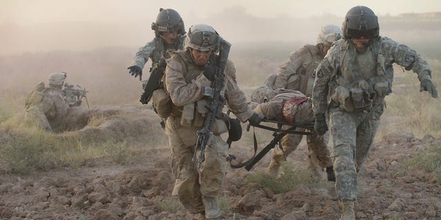MARJA, AFGHANISTAN - SEPTEMBER 23: Army MEDEVAC helicopter crew members with Dustoff Task Force Shadow of the 101st Combat Aviation Brigade help Marines carry a severely wounded Marine to a helicopter on September 23, 2010 near Marja, Afghanistan. The Marine later died of his injuries. (Photo by Scott Olson/Getty Images)