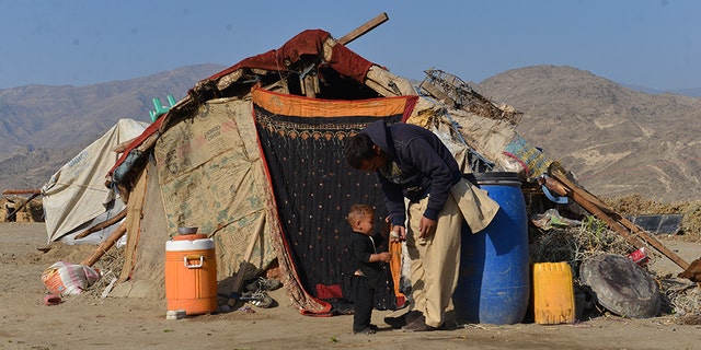 A man who recently came back to Afghanistan from Pakistan plays with his son outside their tent in a camp for returnees.
