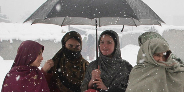 Feb. 20: Afghan refugee women wait with their children to receive donations at a refugee camp in Kabul.
