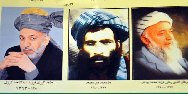 FILE - In this Thursday, July 30, 2015. file photo, an Afghan shop clerk shows a calendar with pictures of Afghan leaders including Mullah Mohammad Omar, center, in Kandahar, south of Kabul, Afghanistan. The new leader of the Afghan Taliban faces the challenge of bringing together an insurgency that he ran under another’s name and uniting a fractured movement that has seen fighters desert for more extreme groups such as the Islamic State. For its part, the Afghan government believes it can seize the on the crisis it has created by announcing that Mullah Mohammad Omar has been dead for more than two years ago to further weaken the insurgency by exposing the lie that had been holding it together. (AP Photo/Barialai Khoshhal, File)
