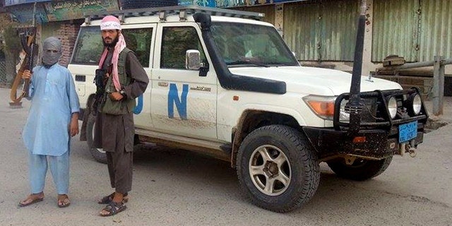 FILE - In this Sept. 29, 2015 file photo, Taliban fighters pose for a photo next to a UN vehicle they plundered in Kunduz, Afghanistan. (AP Photo/File)