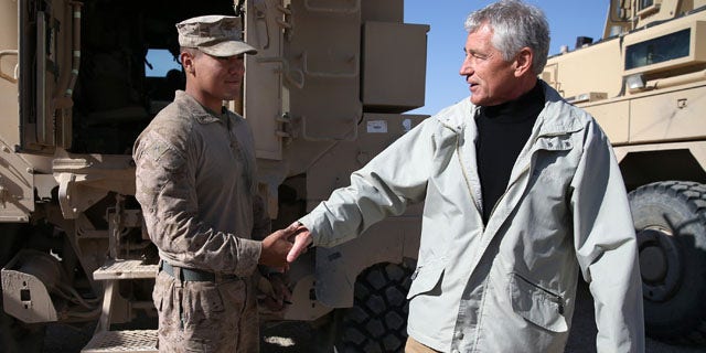 December 8, 2013: U.S. Secretary of Defense Chuck Hagel, right, shakes hands with U.S. Marine Lance Cpl. Arron Corona as he works on a MRAP vehicle, at Camp Bastion, Afghanistan. Hagel spoke with troops and thanked them for being deployed for the holidays. (AP Photo/Mark Wilson, Pool)