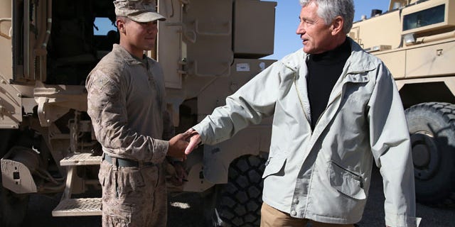 December 8, 2013: U.S. Secretary of Defense Chuck Hagel, right, shakes hands with U.S. Marine Lance Cpl. Arron Corona as he works on a MRAP vehicle, at Camp Bastion, Afghanistan. Hagel spoke with troops and thanked them for being deployed for the holidays. (AP Photo/Mark Wilson, Pool)