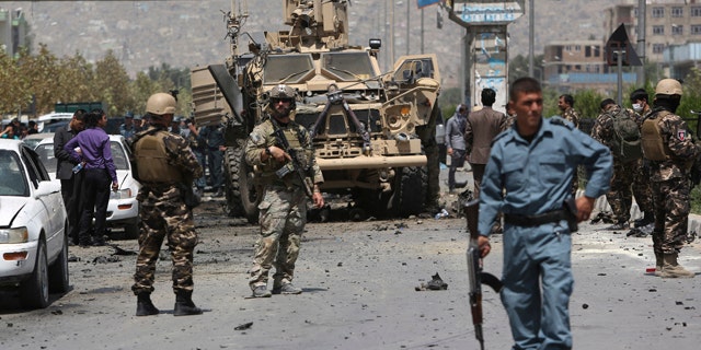 August 10, 2014: NATO and Afghan security forces stand guard at the site of a suicide attack in Kabul. A suicide car bomber attacked a NATO convoy, killing several civilians and wounding more than 35 in an assault claimed by the Taliban, authorities said. (AP Photo/Rahmat Gul)