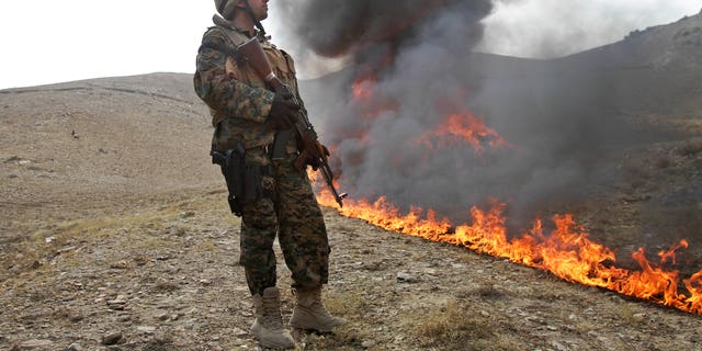 Oct. 14, 2012: An Afghan counternarcotic policeman (CNPA) secures the area as 25 tons of drugs and drug-making gear are burned on the outskirts of Kabul, Afghanistan.