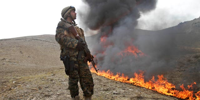 Oct. 14, 2012: An Afghan counternarcotic policeman (CNPA) secures the area as 25 tons of drugs and drug-making gear are burned on the outskirts of Kabul, Afghanistan.