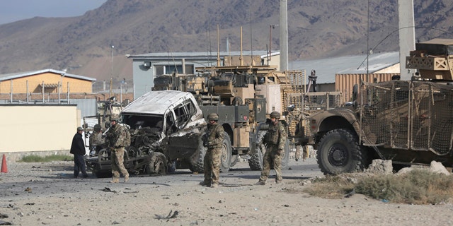 October 13, 2014: U.S. soldiers remove a destroyed vehicle from the site of a suicide attack in Kabul, Afghanistan. (AP Photo/Massoud Hossaini)