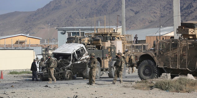 October 13, 2014: U.S. soldiers remove a destroyed vehicle from the site of a suicide attack in Kabul, Afghanistan. (AP Photo/Massoud Hossaini)
