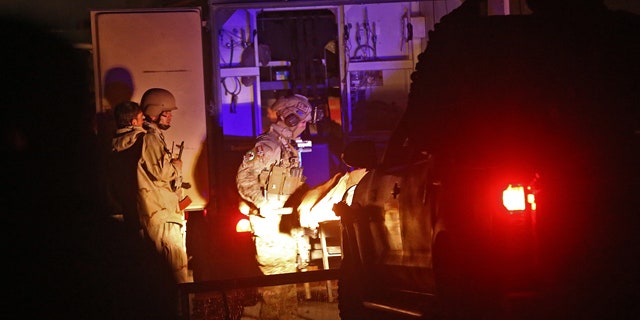 November 29, 2014: Afghan security personnel carry a dead body into an ambulance at the site of a battle between security forces and Taliban fighters in Kabul. (AP Photo/Massoud Hossaini)