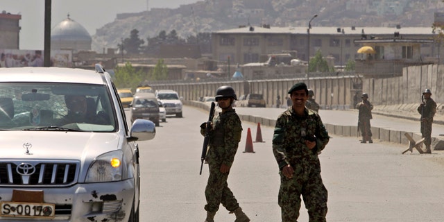 April 18: Afghan security officers secure the road near the Defense Ministry in Kabul, Afghanistan.