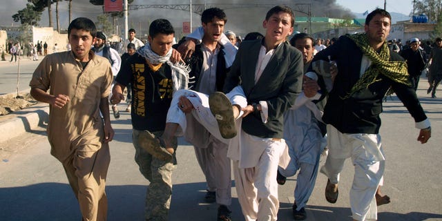 Afghans carrying a man, who got wounded following an attack on UN's office during a demonstration to condemn the burning of a copy of the Muslim holy book by a Florida pastor, in Mazar-i- Sharif north of Kabul, Afghanistan on Friday, April. 1, 2011. An Afghan official says seven people have been killed at a U.N. office in the northern city of Mazar-i-Sharif when a Koran burning protest turned violent.