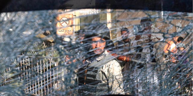 Mar. 6, 2012: An Afghan soldier passes by a chattered window of a destroyed police car after an explosive device went off in the center of Jalalabad, east of Kabul, Afghanistan.