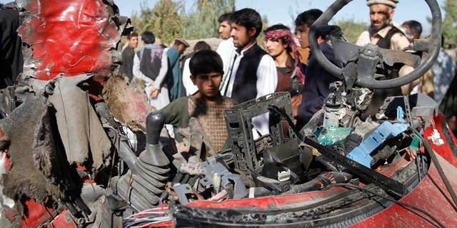 Nov. 12, 2011: Afghans stand around wreckage of a civilian car, which was hit by a roadside bomb in Laghman, east of Kabul, Afghanistan.
