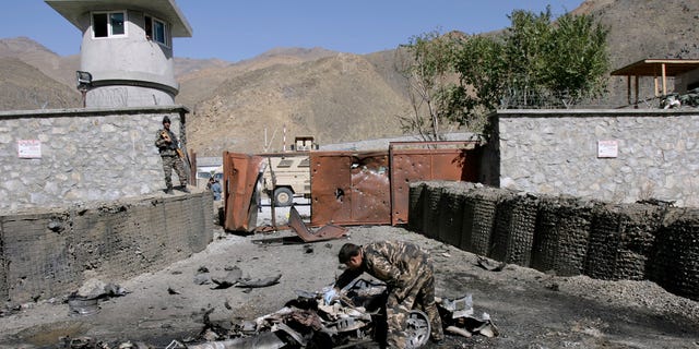 An Afghan security officer, center, collects evidence from the site of an attack by militants at the gate of an American base in Panjshir north of Kabul, Afghanistan, Saturday, Oct. 15, 2011.