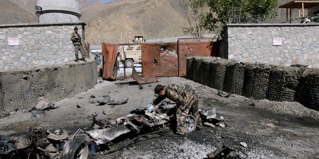 An Afghan security officer, center, collects evidence from the site of an attack by militants at the gate of an American base in Panjshir north of Kabul, Afghanistan, Saturday, Oct. 15, 2011.