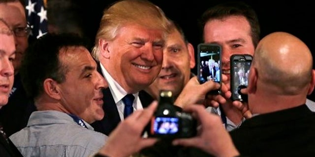 Republican presidential candidate, businessman Donald Trump smiles as he has his photograph taken with supporters after being endorsed at a regional police union meeting in Portsmouth, N.H., Thursday, Dec. 10, 2015. (AP Photo/Charles Krupa)