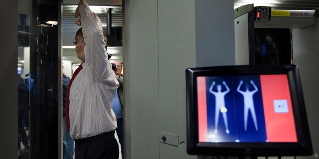 An employee of Schiphol stands inside a body scanner during a demonstration at a press briefing at Schiphol airport, Netherlands. The Netherlands announced Wednesday, Dec. 30, it will immediately begin using full body scanners for flights heading to the United States, issuing a report that called the failed Christmas Day airline bombing a "professional" terror attack.