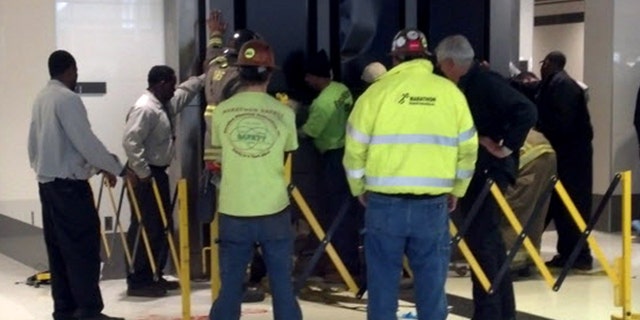 March 22: People hold up a message board sign that fell on a family killing a child and injuring the mother and two other children in the terminal at the Birmingham-Shuttlesworth International Airport in Birmingham, Ala.