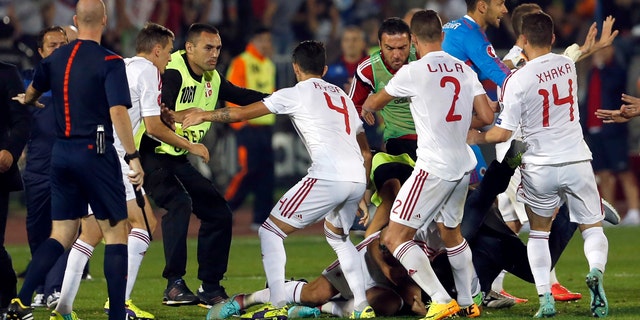 A skirmish between Serbian and Albanian players breaks out on the pitch during the Euro 2016 Group I qualifying match between Serbia and Albania in Belgrade, Serbia, Tuesday, Oct. 14, 2014. The European Championship qualifier between Serbia and Albania was suspended on Tuesday after pitch skirmishes involving players and fans over an Albanian flag that was flown above the stadium by a drone. (AP Photo/Marko Drobnjakovic)