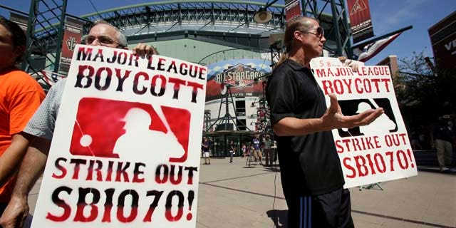 Raul Cordero, left, and Jorge Mandez protest Arizona's immigration law SB1070 outside of Chase Field before the Home Run Derby for the MLB All-Star baseball game Monday, July 11, 2011, in Phoenix. (AP Photo/Matt York)