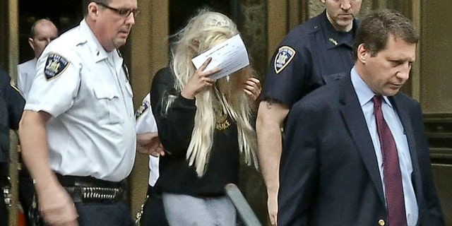 May 24, 2013: In an image made from video, actress Amanda Bynes, center, wearing sweats and a blonde wig, shields her face as she is escorted after a Manhattan criminal court appearance in New York.