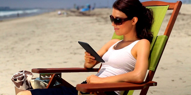 A woman reads an Amazon Kindle ebook reader at the beach. The Internet retail giant is widely expected to be planning a larger tablet PC to compete with the iPad..