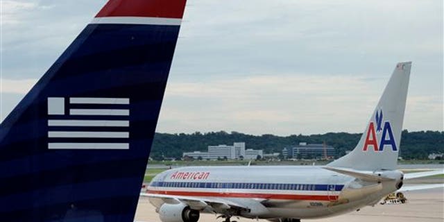 FILE - In this Tuesday, Aug. 13, 2013, file photo, an American Airlines plane and a US Airways plane are parked at Ronald Reagan National Airport in Washington. A Federal bankruptcy judge is approving the settlement in the U.S. government's antitrust lawsuit against American Airlines and US Airways, clearing the airlines to complete their merger early December 2013. (AP Photo/Susan Walsh, File)