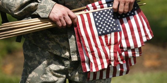 A member of the Third U.S. Infantry Regiment (The Old Guard) carries flags during a "Flags-In" ceremony at Arlington National Cemetery in Washington.