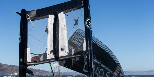 Oct. 16, 2012: Photo provided by Oracle Team USA, crew members hang from the mesh netting after the Oracle Team USA AC72 boat capsized on San Francisco Bay in San Francisco.