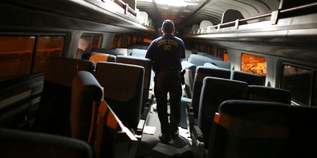 A crime scene investigator looks inside a train car after a train wreck, Tuesday, May 12, 2015, in Philadelphia. An Amtrak train headed to New York City derailed and crashed in Philadelphia. (AP Photo/Joseph Kaczmarek)