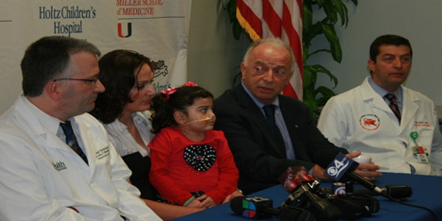 Angela Bushi sits with her mother, along with her surgeon Dr. Andreas Tzakis and the geneticist who diagnosed her, Dr. Olaf Bodamer, as they announce the success of their groundbreaking surgery.