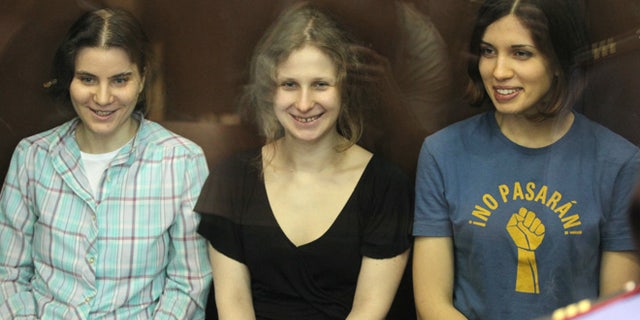 Aug. 17, 2012: Nadezhda Tolokonnikova, right, Yekaterina Samutsevich, left, and Maria Alekhina, center, members of feminist punk group Pussy Riot seen behind a glass wall at a court in Moscow, Russia.