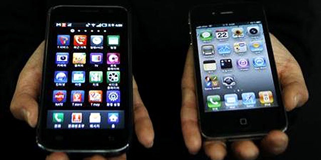 April 22, 2011: An employee of South Korean mobile carrier KT holds a Samsung Galaxy S (L) and an Apple iPhone 4 (R) at KT's headquarters in Seoul.