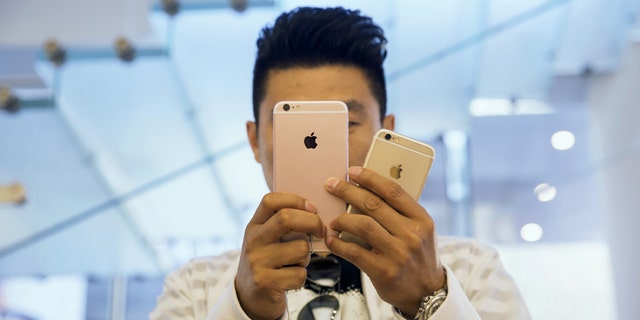 A man takes pictures as Apple iPhone 6s and 6s Plus go on sale at an Apple Store in Beijing, China Sept. 25, 2015.