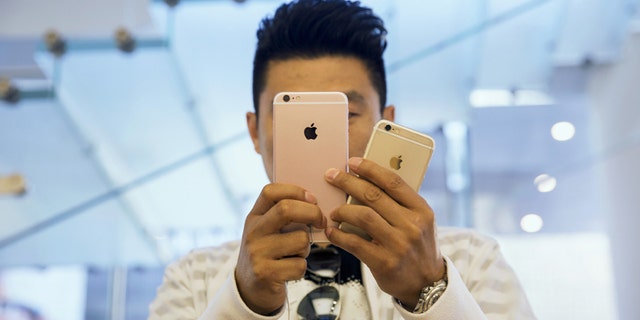 A man takes pictures as Apple iPhone 6s and 6s Plus go on sale at an Apple Store in Beijing, China Sept. 25, 2015.