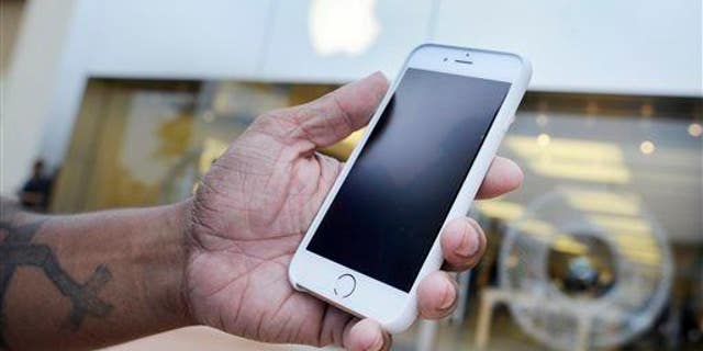 A customer holds his new iPhone 6 at an Apple Store in Augusta, Ga.