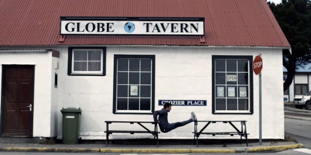 In this frame grab from a TV advertisement released by Argentine Presidential Office, an Argentine Olympic field hockey player Fernando Zylberberg exercises in front of the Globe Tavern in Stanley, Falkland Islands.